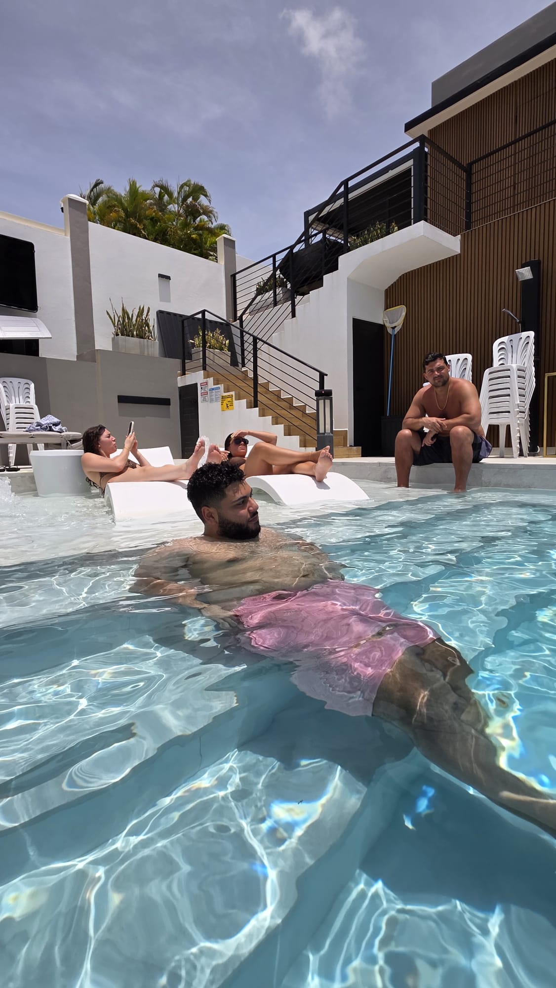 Guests relaxing in the private swimming pool and on poolside lounge chairs at Blue Malibu PR